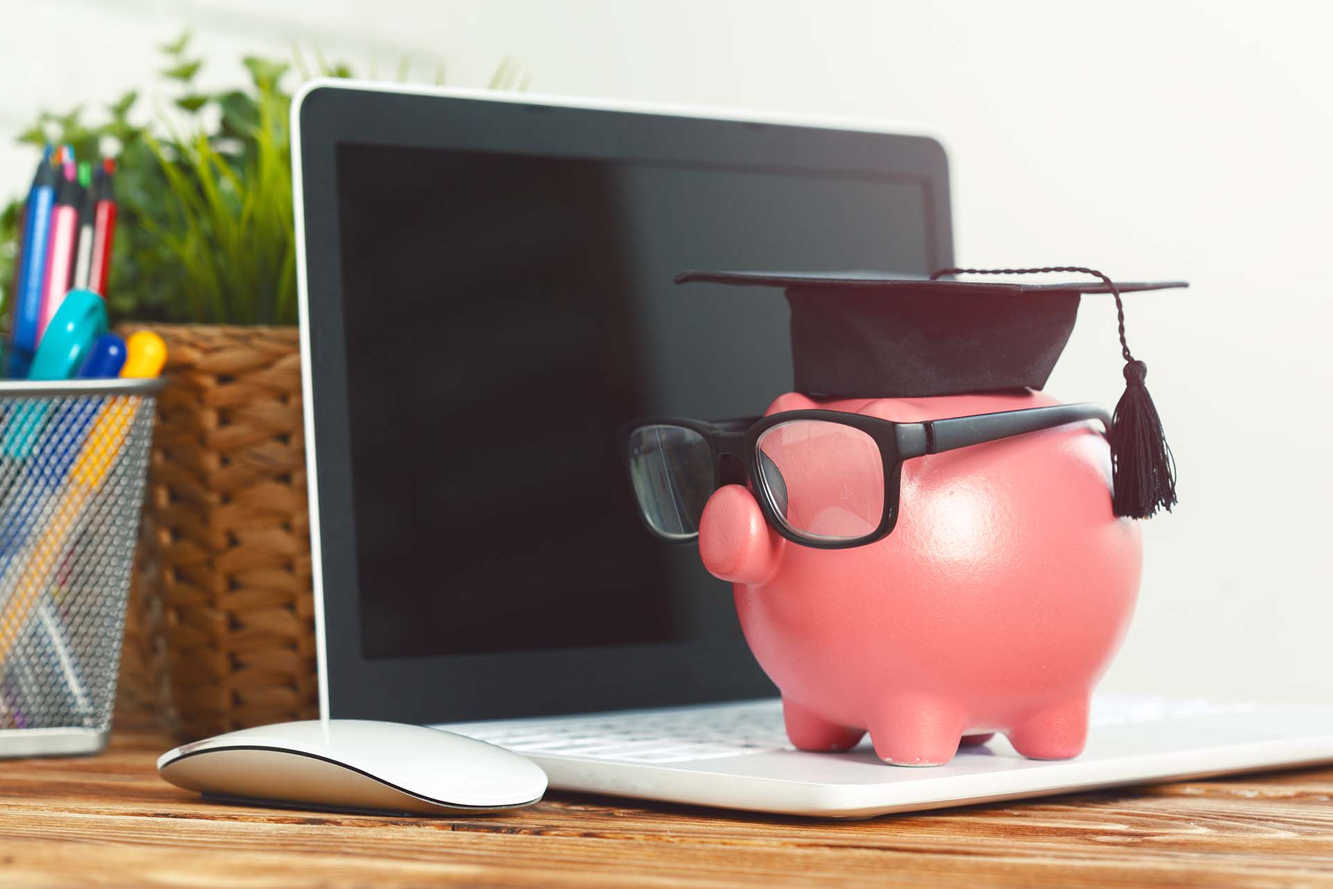 Piggy money box with laptop on wooden table
